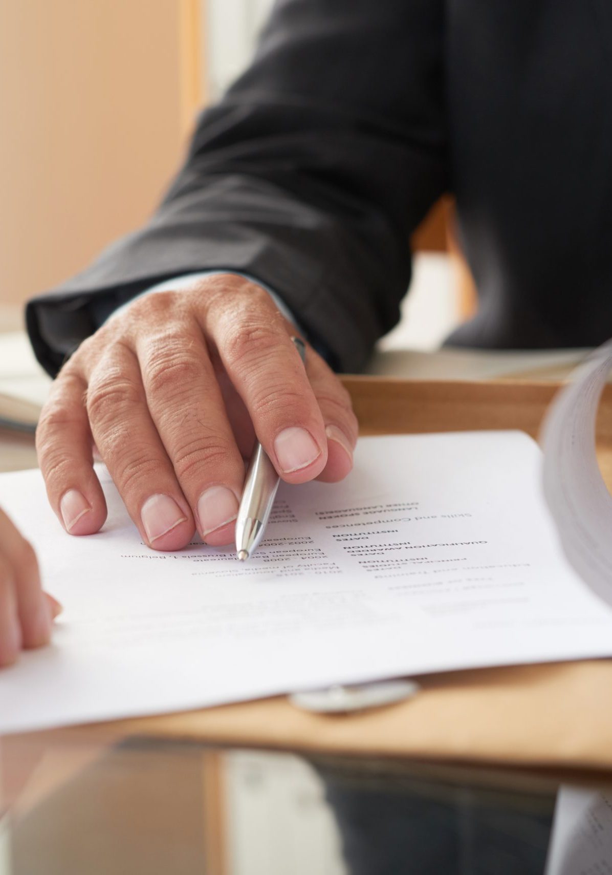 Close-up of businessman examining business contract and signing it at the office desk